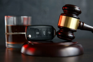 a judges gavel with car keys and a drink