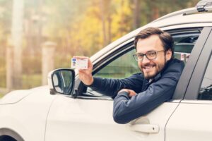 man holding a license out of a car window