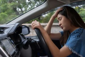 woman in car with her hand on her head