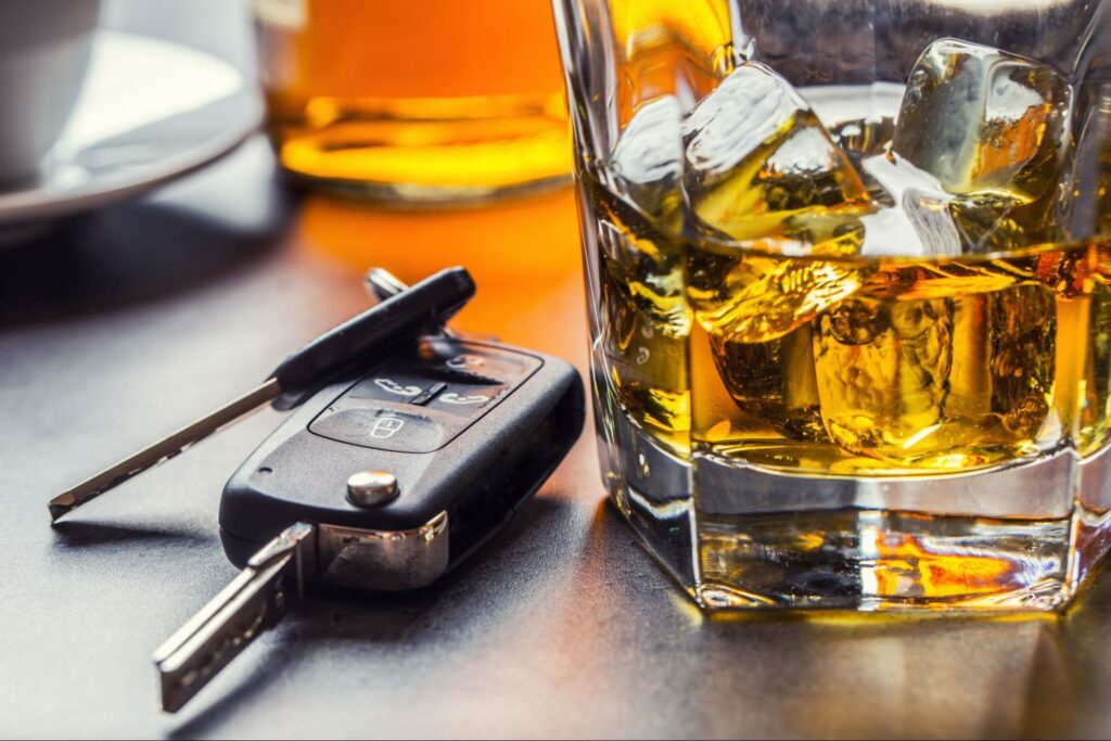 A glass of whisky sitting next to car keys