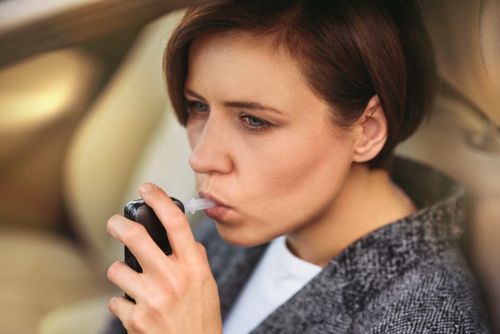 a woman in a car blowing into a breathalyzer