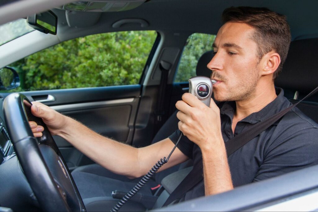 man blowing into an ignition interlock device