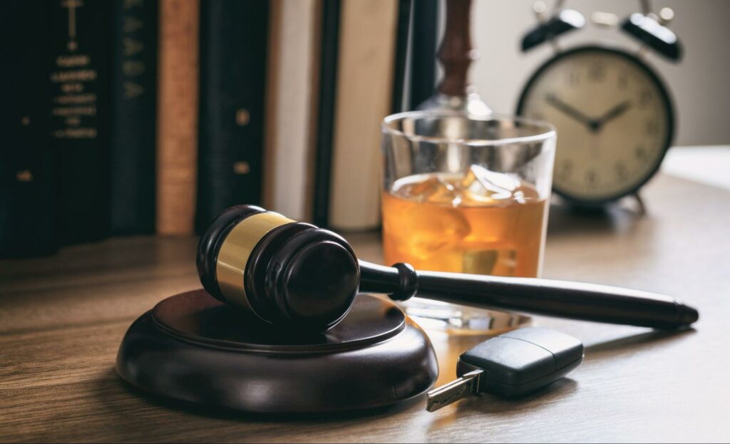 judges gavel next to car keys and a glass of alchohol