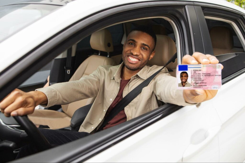 man holding his driver's license out of a car window
