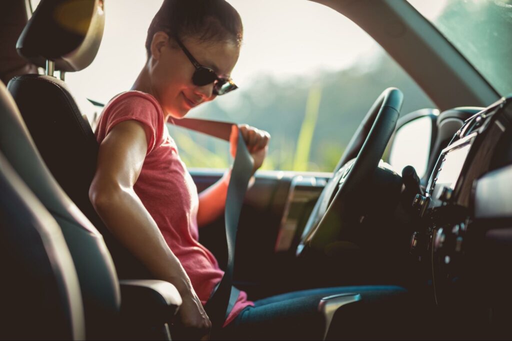 woman buckling her seatbelt to follow safe driving tips