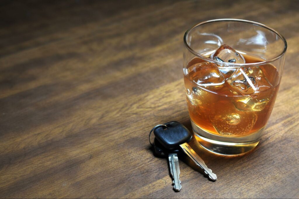 car keys sitting next to a glass of alchohol