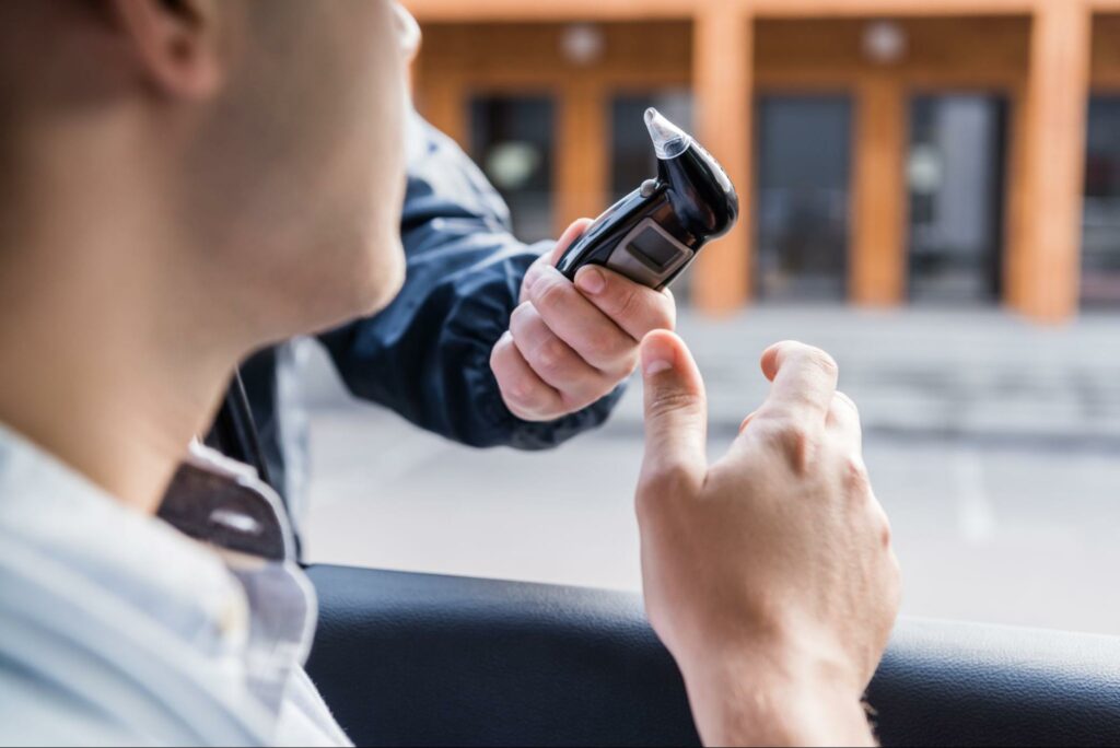 A driver accepting a breathalyzer test from a police officer