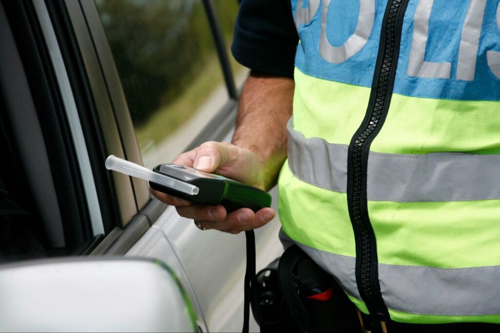 Police officer offering a breathalyzer test to a driver