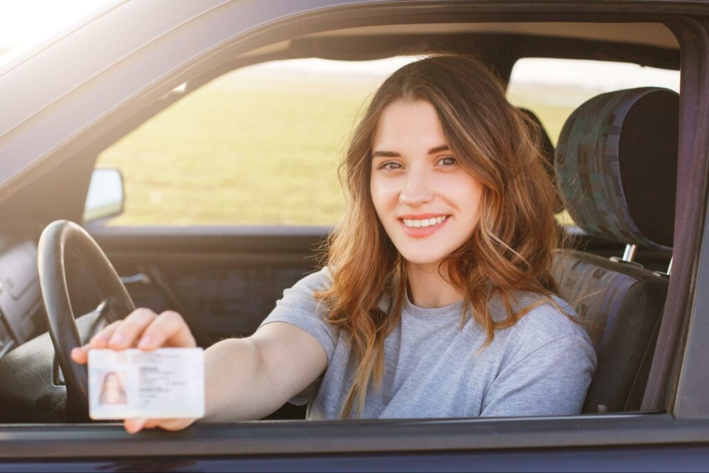 Woman showing a driver's license out of a car window